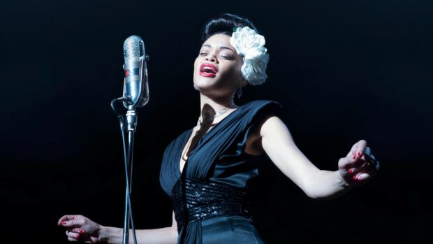 A jazz singer expressing emotion while performing on stage with vintage microphone and flower in hair