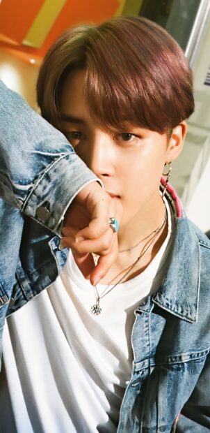 Close up of Jimin in a denim jacket and white shirt looking thoughtful