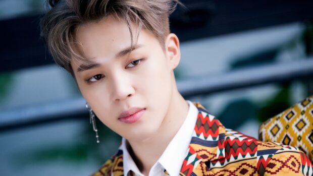 Jimin in a colorful patterned jacket posing thoughtfully with a soft expression