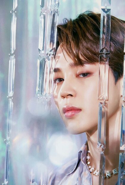 A close up of Jimin surrounded by crystal decorations with a calm expression