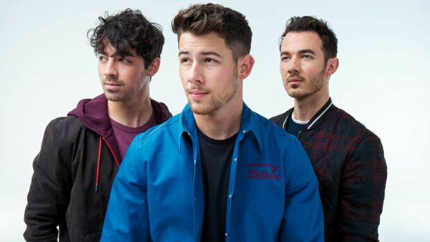 The Jonas Brothers standing together in casual outfits with serious expressions