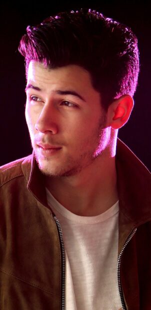 Close up of Jonas Brothers member looking away with pink lighting on face