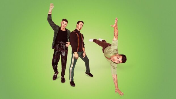 Jonas Brothers standing and posing energetically on a green background