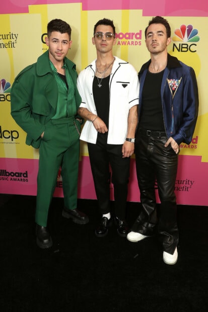 The Jonas Brothers posing together at a music awards event in stylish outfits