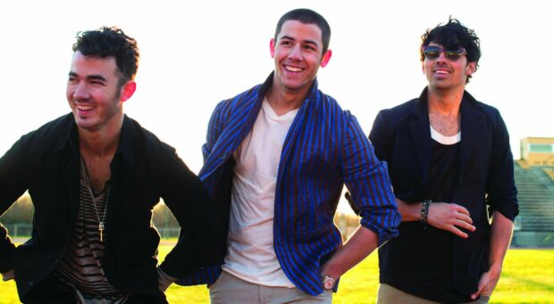 The Jonas Brothers smiling and enjoying outdoors in casual outfits