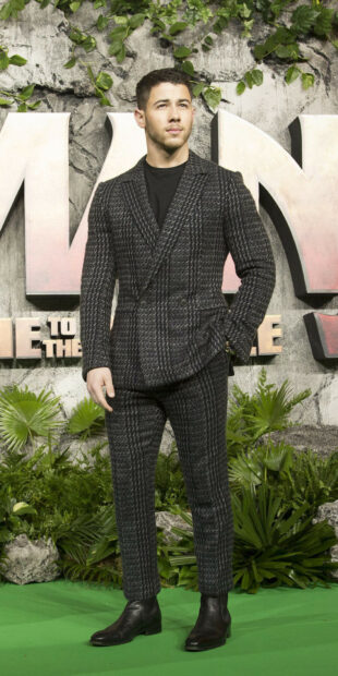 Jonas Brothers wearing a patterned suit standing on a green carpet at an event