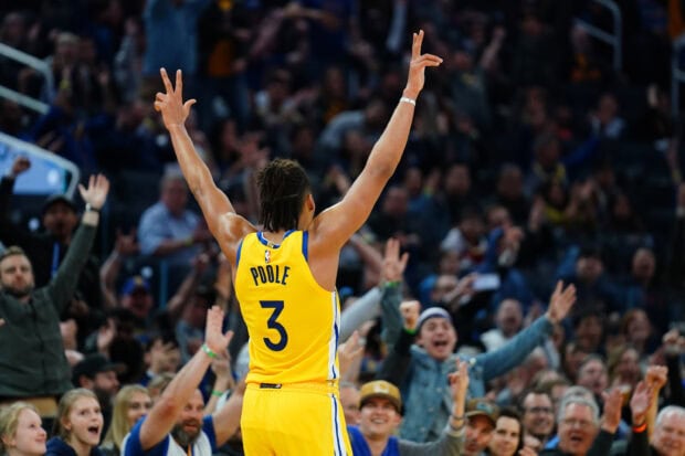 Jordan Poole celebrating with arms raised during a basketball game amid cheering fans