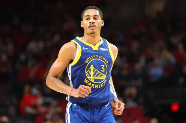 Jordan Poole wearing Golden State Warriors jersey running on court during basketball game