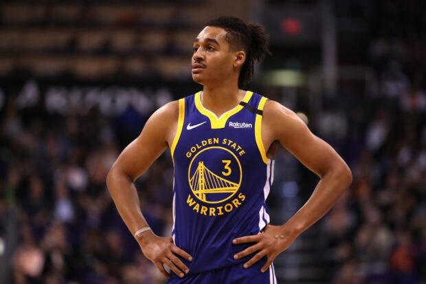 Jordan Poole wearing Golden State Warriors jersey standing with hands on hips during a basketball game