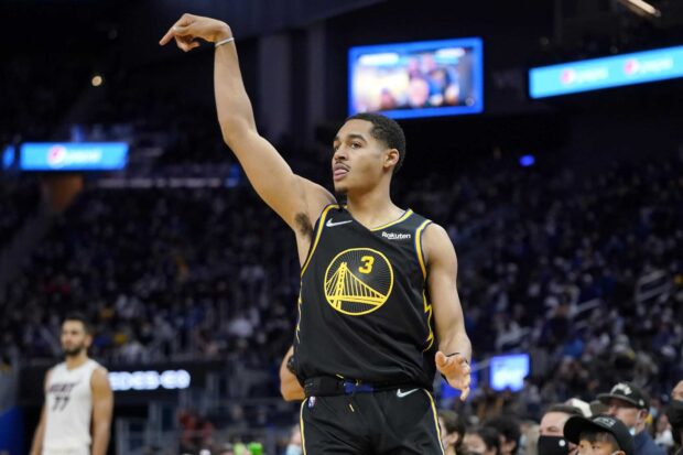 Jordan Poole is a basketball player shooting a three point in an NBA game