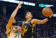 Jordan Poole driving to the basket during a basketball game against the Utah Jazz defender