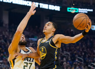 Jordan Poole driving to the basket during a basketball game against the Utah Jazz defender