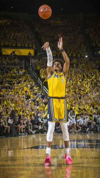 Jordan Poole shooting a basketball in a Michigan basketball game in front of a cheering crowd