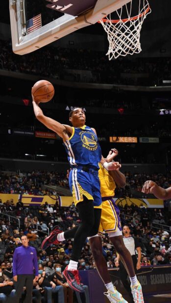 Jordan Poole jumping to dunk a basketball during a game wearing the Warriors jersey