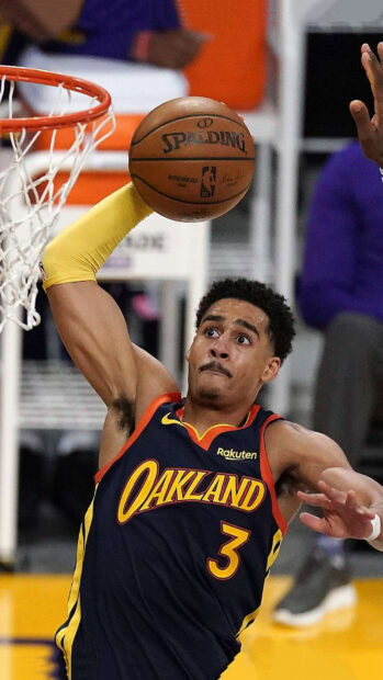 Jordan Poole performing a slam dunk during a basketball game in an Oakland jersey