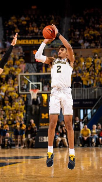 Jordan Poole wearing Michigan uniform preparing to shoot a basketball during a game