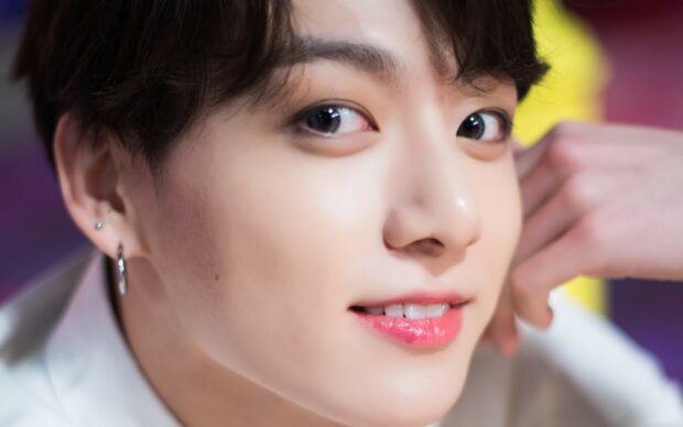 Close up of Jungkook smiling with shiny earrings and smooth skin
