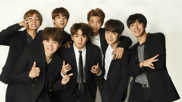 Jungkook group posing together in stylish black suits with friendly expressions