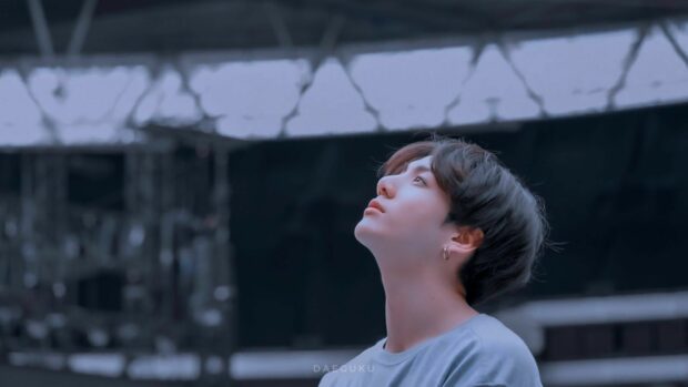 Jungkook looking thoughtfully upward in a serene setting with soft lighting