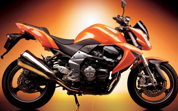 Orange Kawasaki motorcycle detailed side view against orange gradient background