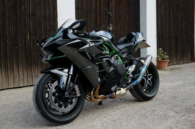 A Kawasaki sport motorcycle parked in front of wooden garage doors on a concrete surface