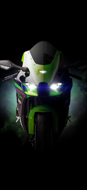Front view of a Kawasaki motorcycle with bright headlights in a dark foggy setting