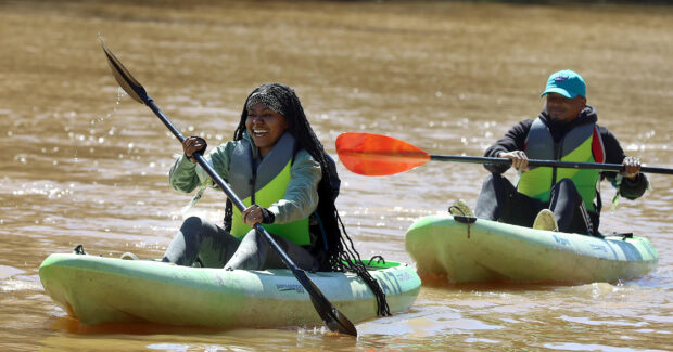 Two people enjoying kayaking on calm water in a sunny day