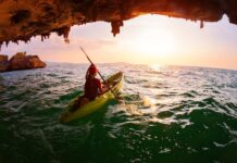 A person kayaking through a sea cave with scenic ocean views at sunset
