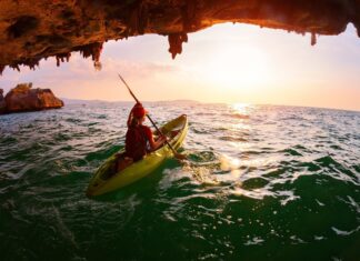 A person kayaking through a sea cave with scenic ocean views at sunset