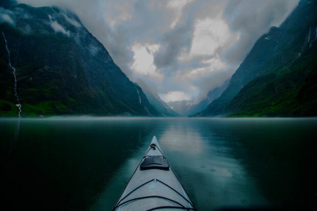 A kayak journey through a misty fjord surrounded by steep mountains and waterfalls