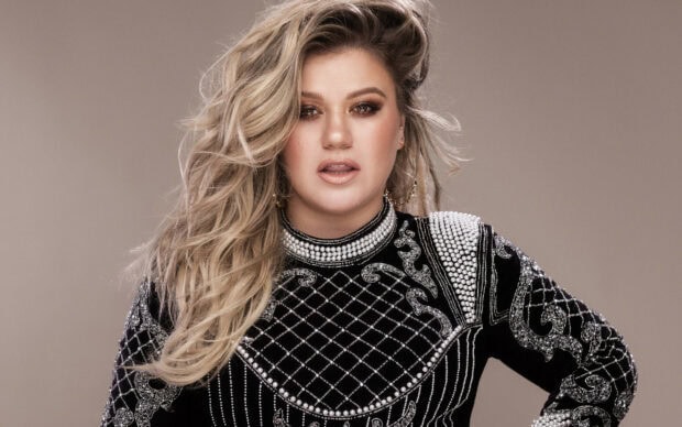 Kelly Clarkson wearing a detailed jeweled outfit with long blonde hair flowing