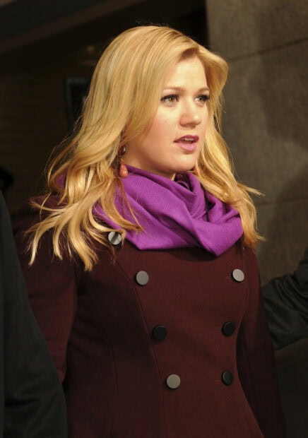 Kelly Clarkson wearing a purple scarf and maroon coat with blonde hair styled naturally