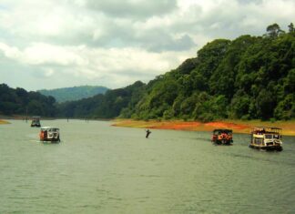 River with boats cruising through lush green Kerala forest landscape