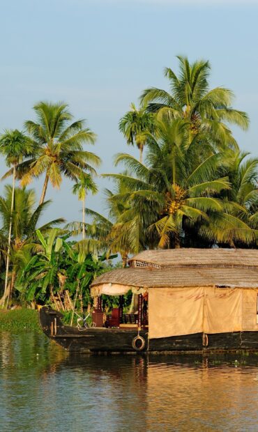 Traditional Kerala houseboat on calm water with palm trees in the background