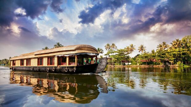 Traditional Kerala houseboat sailing on peaceful water with lush greenery in Kerala
