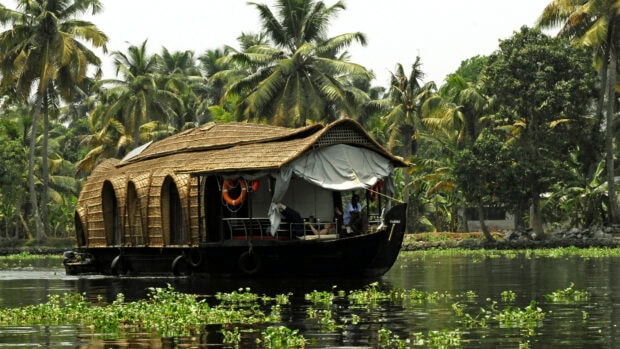 Traditional Kerala houseboat on peaceful water surrounded by palm trees in Kerala