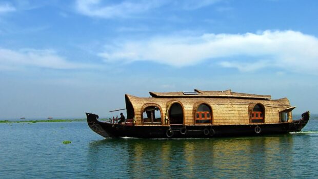 Traditional Kerala houseboat floating on calm water with clear blue sky