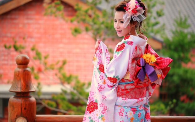 A woman wearing a colorful kimono posing outdoors with a traditional hairstyle and floral patterns