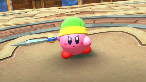 Kirby in a green and yellow hat holding a spear in Kirby And The Forgotten Land