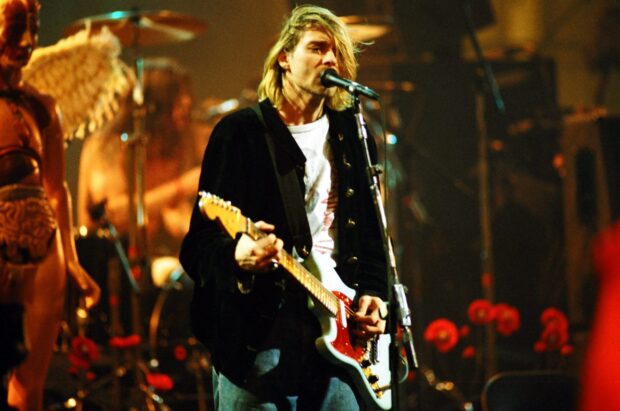 Kurt Cobain playing guitar and singing on stage during a live performance