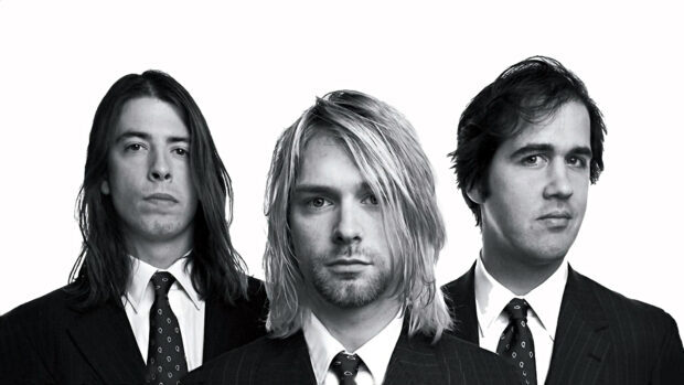 Kurt Cobain and band members wearing suits posing for a black and white portrait