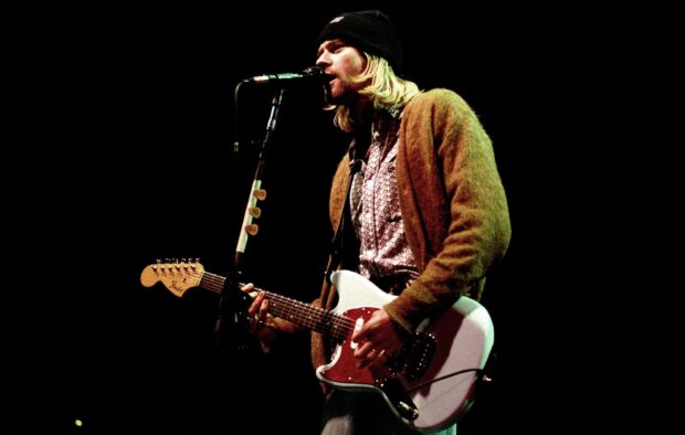 Kurt Cobain playing guitar and singing on stage during a live performance