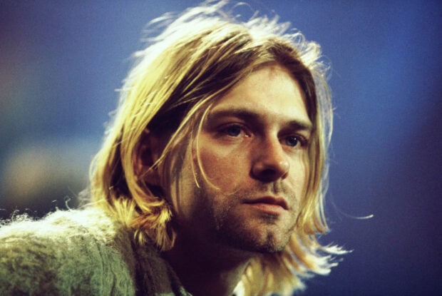 Kurt Cobain with long hair and a thoughtful expression in a close up portrait