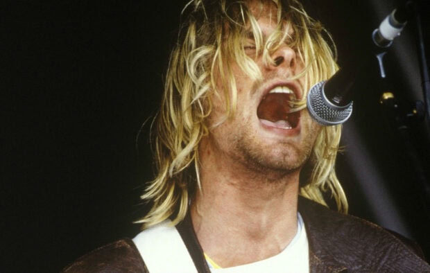 Kurt Cobain passionately singing into a microphone with his hair covering part of his face