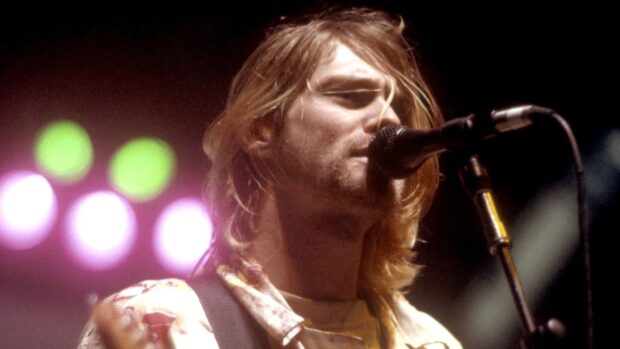 Kurt Cobain singing into a microphone during a live performance on stage