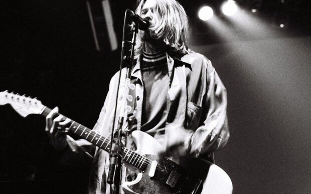 Kurt Cobain playing the guitar on stage during a live performance