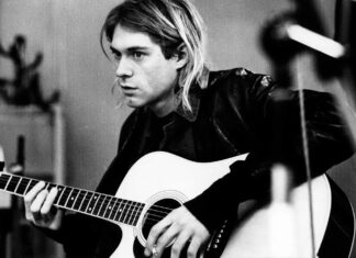 Kurt Cobain playing acoustic guitar in a black and white setting