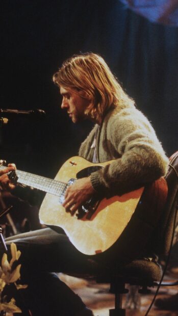 Kurt Cobain playing guitar during a live performance in an intimate setting