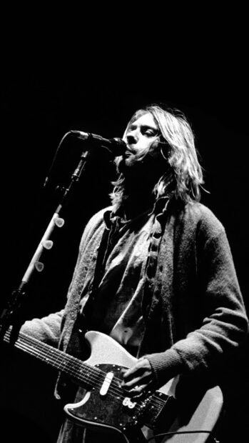 Kurt Cobain performing with guitar on stage in a black and white photo