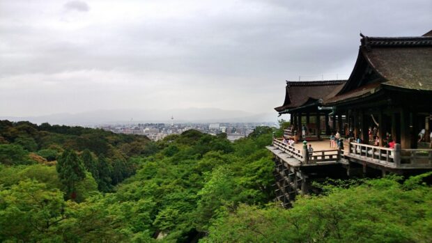 Traditional Kyoto temple overlooking lush green forest and cityscape